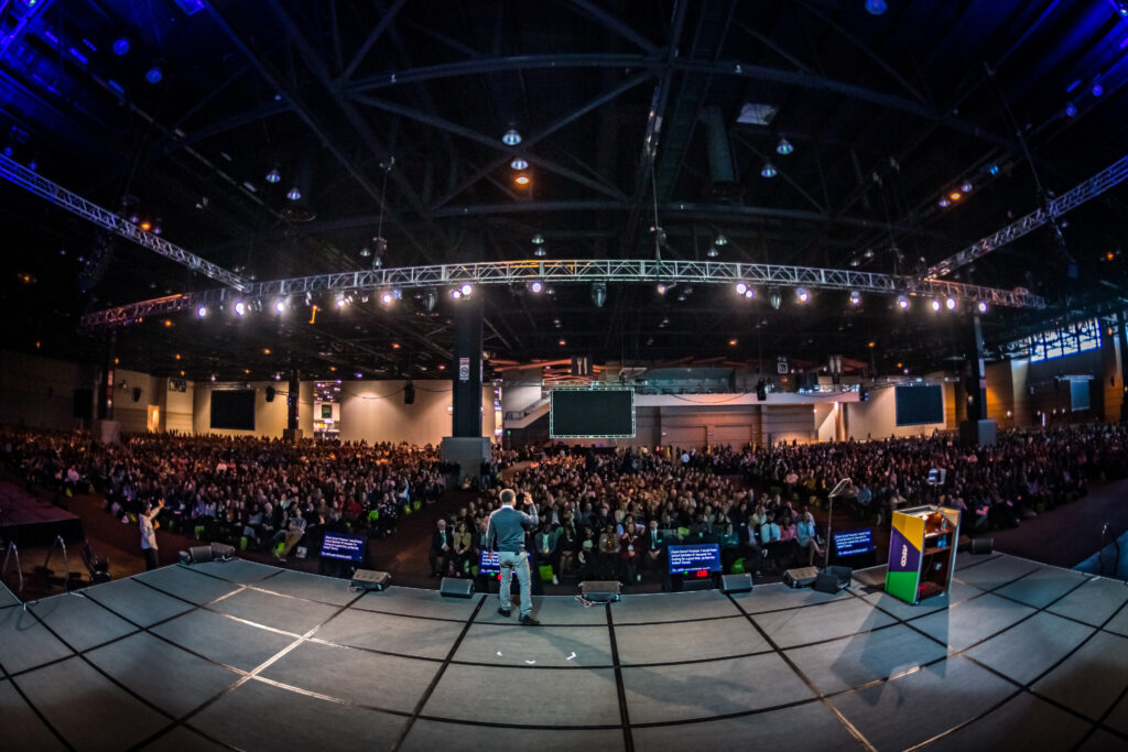 Keynote speaker on stage speaking to a large crowd